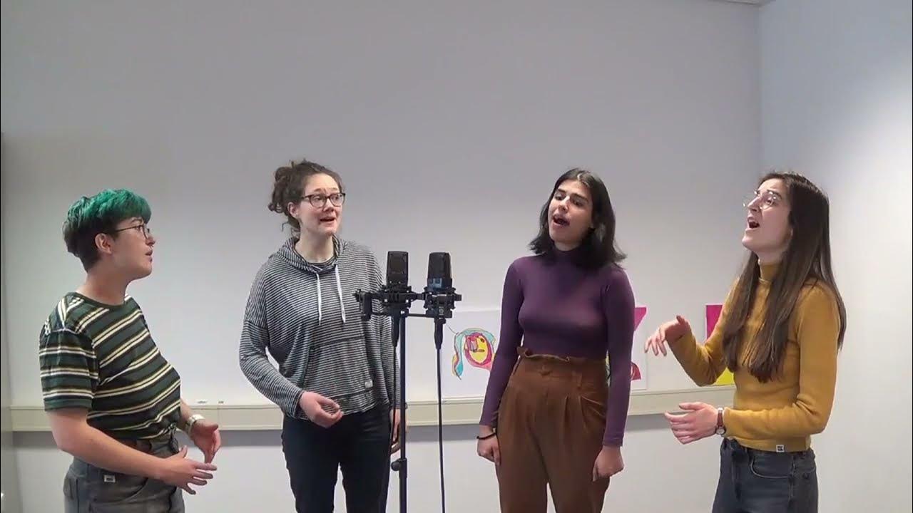 Embedded video: from left to right: Amélie, Tabea, Niki and Marie stand singing in a half circle around a microphone